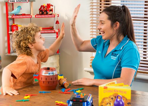 An occupational therapist high fives her young patient
