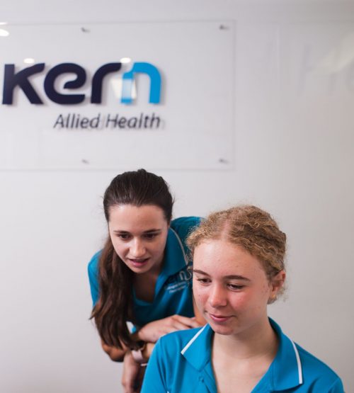 A Kern Allied Health therapist looks over the shoulder of another therapist